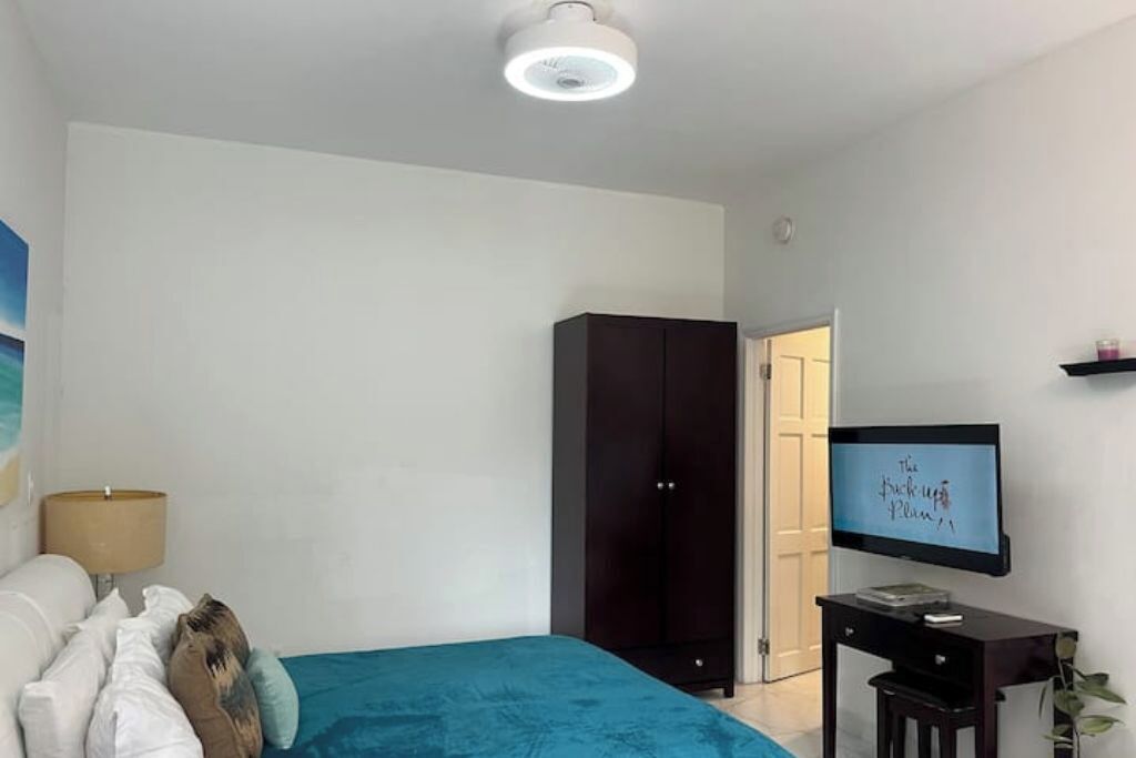 Quarto com cama, guarda-roupa, televisão e escrivaninha.