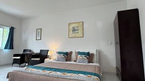 Une chambre à coucher avec un lit, un bureau et deux chaises.