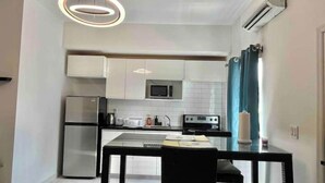 Une cuisine compacte équipée d’un réfrigérateur, d’un four à micro-ondes, d’une cuisinière et d’une table à manger avec des chaises.
