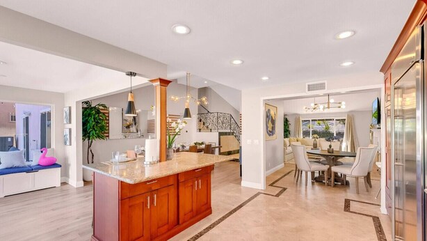 A spacious kitchen with a large island, modern pendant lighting, and a dining area with a table and chairs.