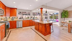 A modern kitchen with wooden cabinets, a central island, and a view to a dining area.