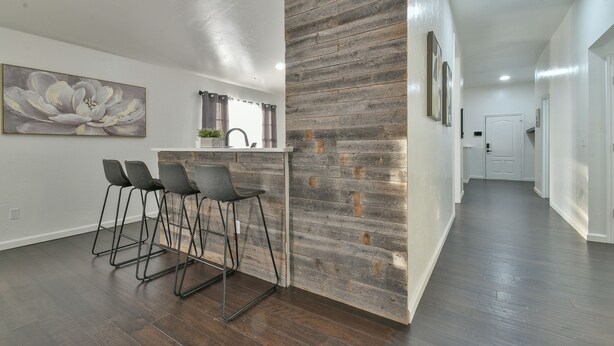 Una cocina moderna con un revestimiento de madera, taburetes de bar y un cuadro grande con motivos florales.