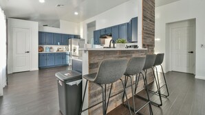 Una cocina moderna con armarios azules, un revestimiento de pared de madera y una zona de bar con taburetes.