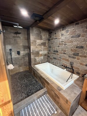 Une salle de bain moderne avec une douche en pierre, une baignoire et un plafond en bois.