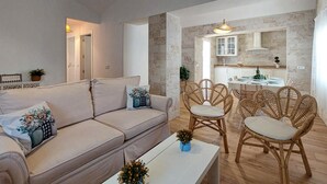 Een woonkamer met een bank, stoelen, een salontafel, en een keuken met een eettafel en stoelen.