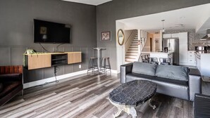 Una sala de estar moderna con un sofá gris, una mesa de centro negra y un televisor montado en la pared.