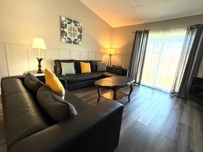 A modern living room with a sofa, a coffee table, and a painting on the wall.
