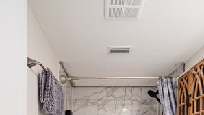 Et badeværelse med badekar, toilet og marmorfliser.