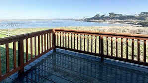 A wooden deck with a railing overlooking a beach and ocean. - The Coquille River Retreat (Bandon)
