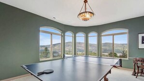 A spacious room with a ping pong table, large arched windows, and a chandelier. - 8,500 sq.ft. Luxurious River/Mountain View house (Kettle Falls)