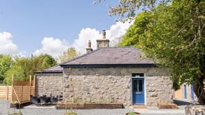 A stone building with a blue door, outdoor seating, and planters.