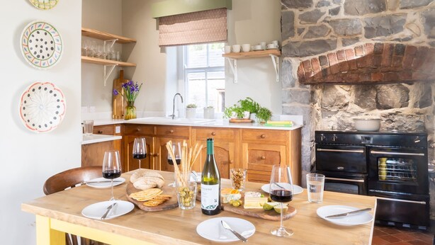 A kitchen with a stone wall, wooden cabinets, and a brick oven.