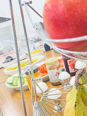 A fruit and snack display with various items like watermelon, bananas, and jars of spreads. - Gästehaus Tilly (Hann. Muenden)