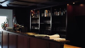 A bar area with a counter, shelves of liquor bottles, and glassware. - Gästehaus Tilly (Hann. Muenden)