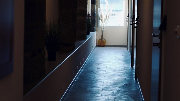 A hallway with stone walls, a potted plant, and a window with a view. - Gästehaus Tilly (Hann. Muenden)