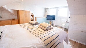 Un dormitorio con cama, armario de madera, televisor y ventana.