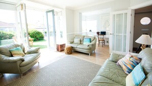 Un salón amplio con un sofá, un tapete estampado y vistas al exterior.