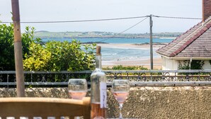 Una mesa con una botella y dos vasos, con vistas a una playa y al océano.