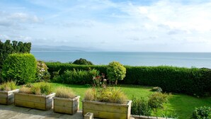 Un giardino con vista sul mare, fioriere in legno e siepi curate.