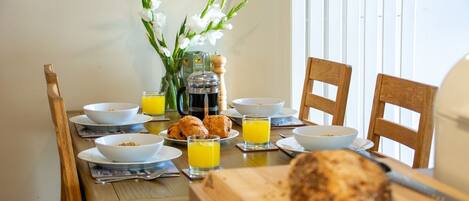 A breakfast table with bowls, croissants, and orange juice glasses.
