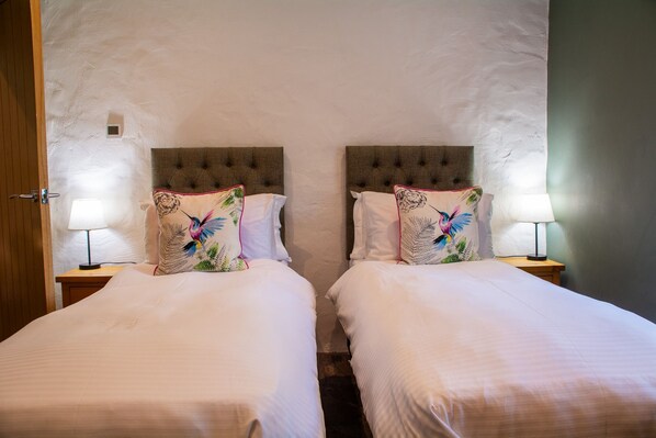 A hotel room with two single beds, each with a headboard and a bedside lamp.