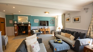 A cozy living room with a fireplace, sofas, and a television. - Goleufryn - sleeps 20 guests  in 7 bedrooms (Abersoch)