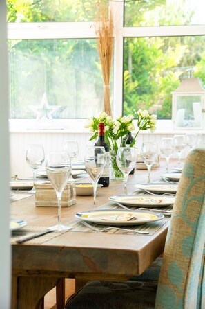 A dining table set for a meal with wine glasses, plates, and a bottle of wine.