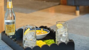 A cozy room with a fireplace, a bottle of tonic water, and glasses with lemon slices on a tray. - Goleufryn - sleeps 20 guests  in 7 bedrooms (Abersoch)