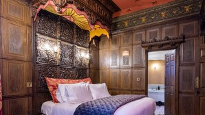 Une chambre à coucher luxueuse, dotée d’un grand lit, de boiseries décoratives et d’un style classique.