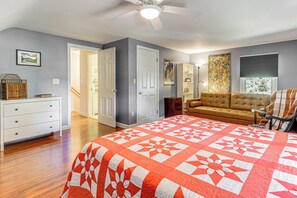 Une chambre à coucher avec un grand lit, un canapé, un ventilateur de plafond et une porte donnant sur une autre pièce.