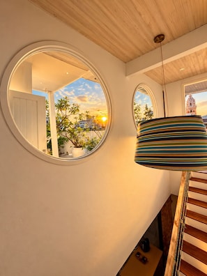A modern interior with a staircase, a round mirror reflecting a sunset, and a striped lamp. - Casa Lazuli 303 Cartagena (Cartagena)