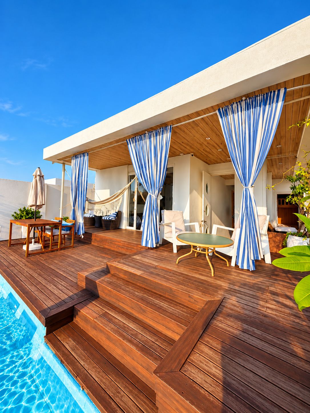 A wooden deck with a pool, outdoor seating, and a covered area with curtains.