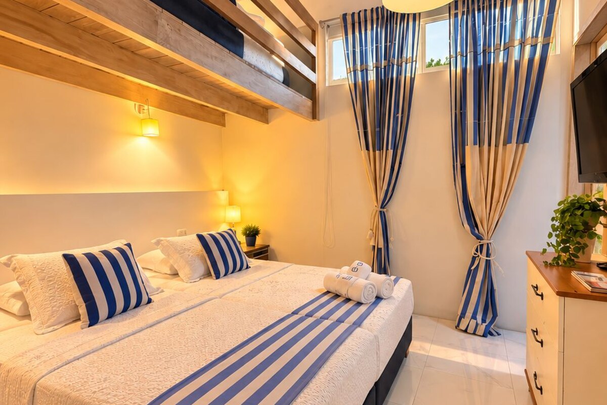 A modern bedroom with a large bed, ceiling fan, and a view of the sky.