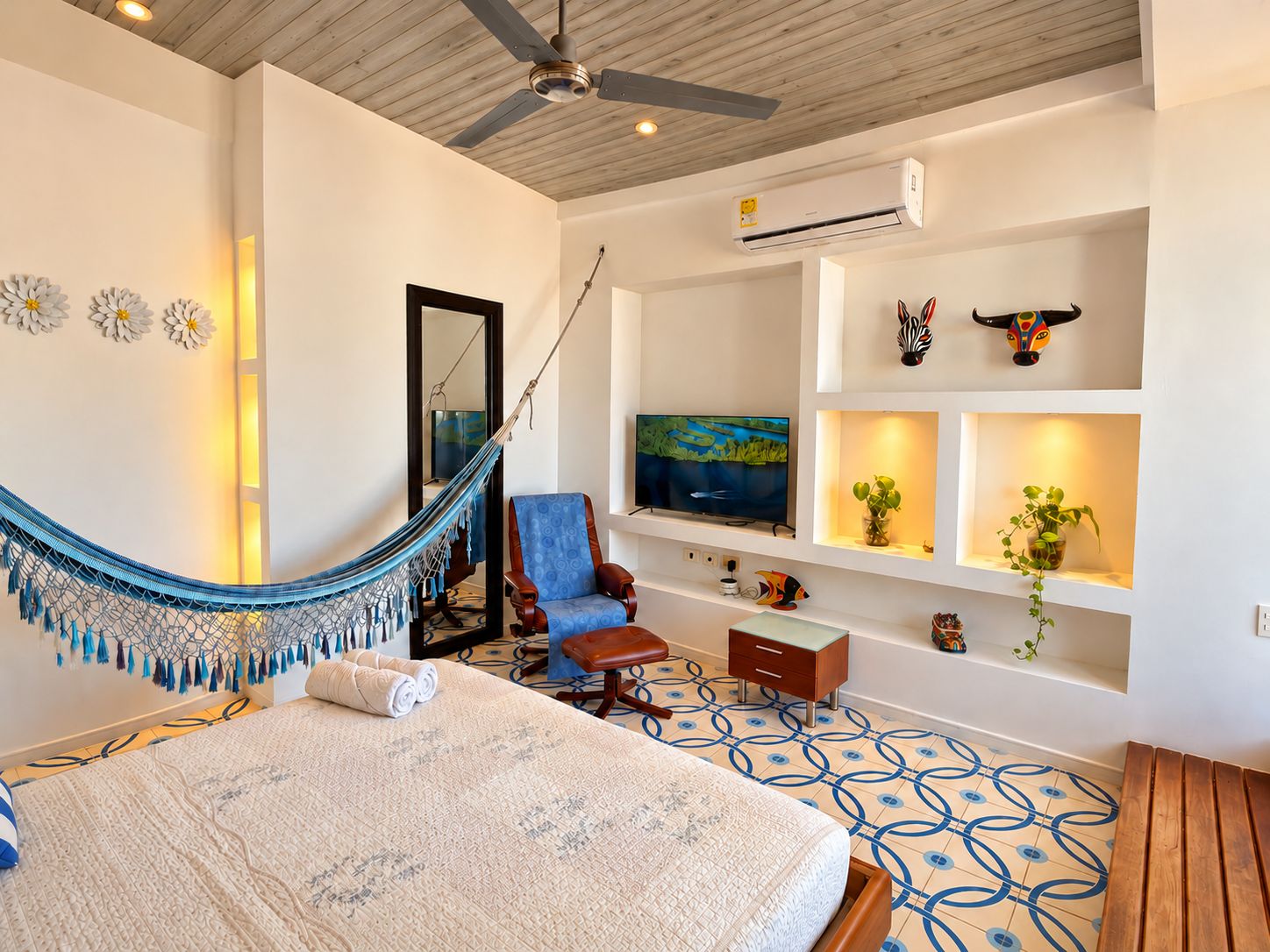 A hotel room with a bed, a hammock, a TV, and a ceiling fan.