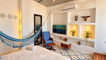 A hotel room with a bed, a hammock, a TV, and a ceiling fan.