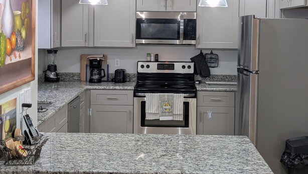 A modern kitchen with granite countertops, stainless steel appliances, and pendant lighting. - Family-friendly•Quiet•Near Beaches, Parks & Cities (Palm Bay)