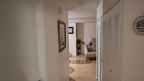 A hallway with a wooden floor, a white door, and a white wall with a framed picture. - Family-friendly•Quiet•Near Beaches, Parks & Cities (Palm Bay)