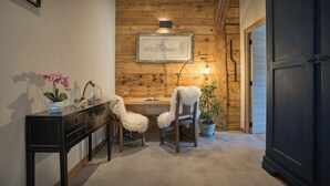 Ein gemütliches Zimmer mit Holzvertäfelung, einem Schreibtisch mit Lampe, zwei Stühlen und einem Blumentopf.