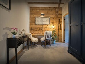 Um quarto aconchegante com painéis de madeira, uma escrivaninha com abajur, duas cadeiras e um vaso de plantas.
