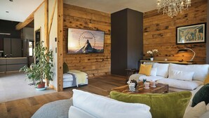 A modern living room with a white sofa, a wooden coffee table, and a chandelier.
