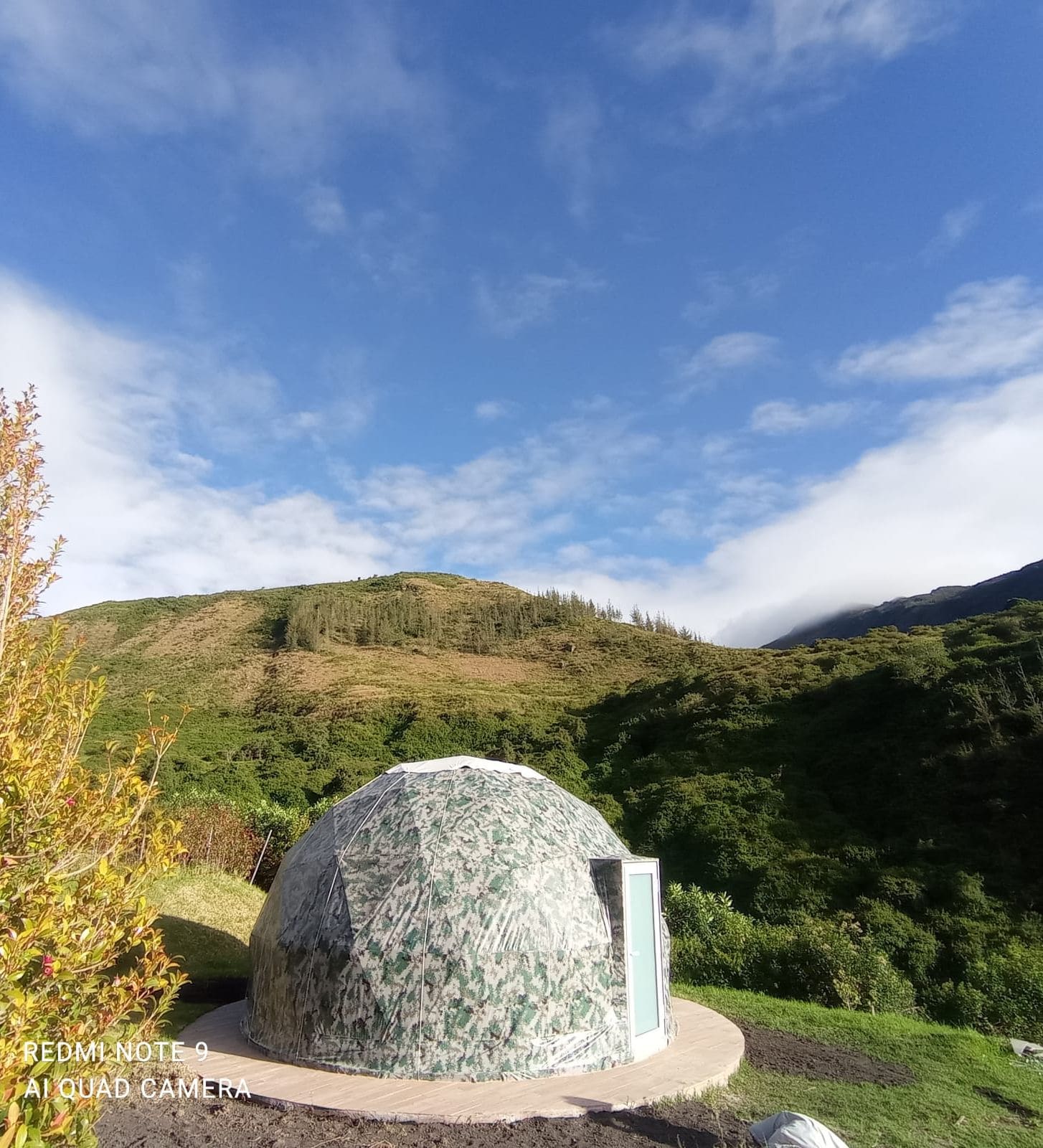 Estrutura em forma de cúpula geodésica em ambiente natural, com céu limpo.
