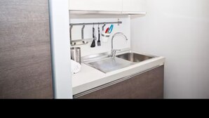 A modern kitchen with a stainless steel sink, white cabinets, and a utensil holder. - Cozy Trastevere Apartment - Great Location, Fast Wi-Fi & A/C (Roma)