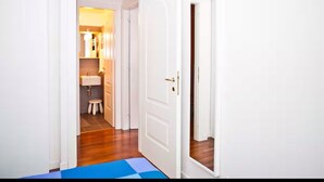 A narrow hallway with a blue mat leading to a white door. - Cozy Trastevere Apartment - Great Location, Fast Wi-Fi & A/C (Roma)