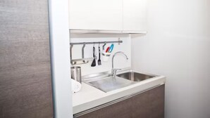 Una cocina moderna con un lavamanos de acero inoxidable, armarios blancos y un portalapices.