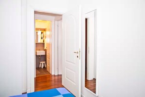 A narrow hallway with a blue mat leading to a white door.