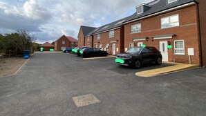 Un parcheggio con diverse auto parcheggiate di fronte a una fila di case in mattoni.