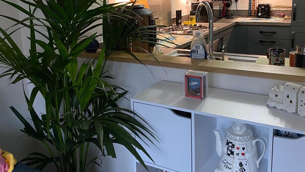 Una cucina moderna con mobili grigi, un'isola centrale e una lampada a sospensione.