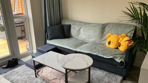 Un soggiorno con un divano grigio, un tavolino rotondo, un tappeto morbido e una pianta in vaso.
