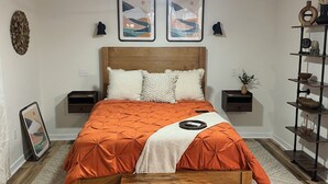 Un dormitorio con una cama de madera, dos mesitas de noche, un ventilador de techo y un estante junto a la cama.