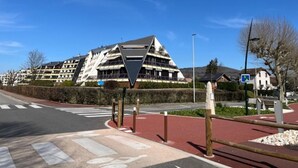 A modern building with a unique triangular roof design, located at a street intersection with a pedestrian crossing.